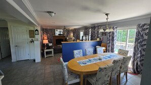 A dining area with a round table, floral chairs, a blue accent wall, and a kitchen in the background. - Lake Anna Waterfront Family & Pet Friendly Retreat! With 5+ BRs 4 BAs. (Spotsylvania Courthouse)