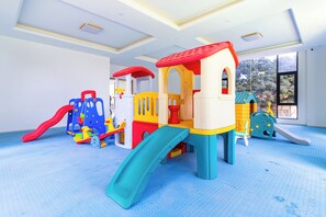 Un'area giochi per bambini con scivolo, strutture di arrampicata e una casetta.