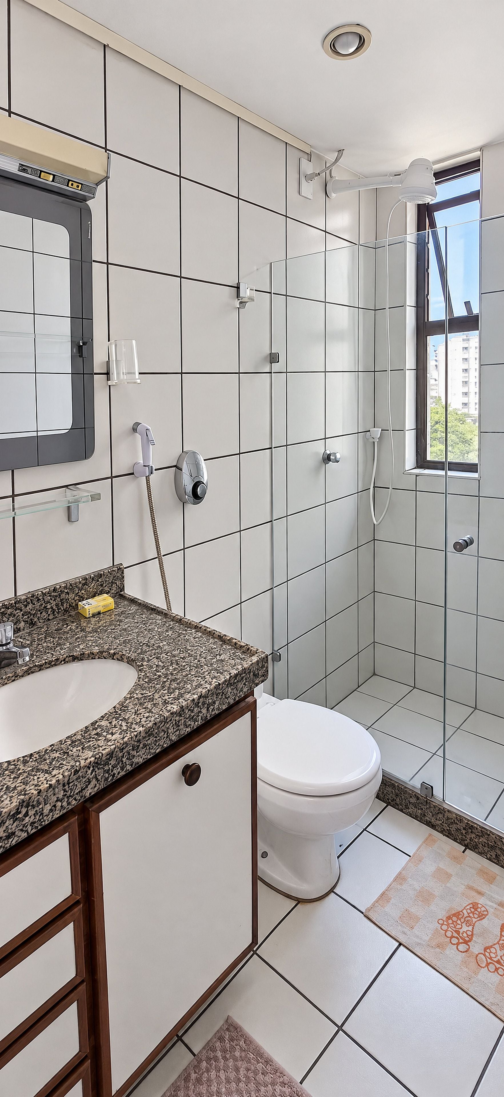 A bathroom with a white toilet, a sink with a granite countertop, and a shower area.