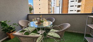A balcony with a glass table, wicker chairs, and a potted plant. - Ape Familia 200 Metros da Feirinha Beira mar 502 (Fortaleza)