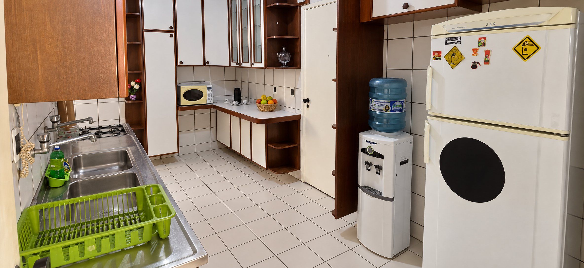 A compact kitchen with a sink, a microwave, a refrigerator, and a water dispenser.