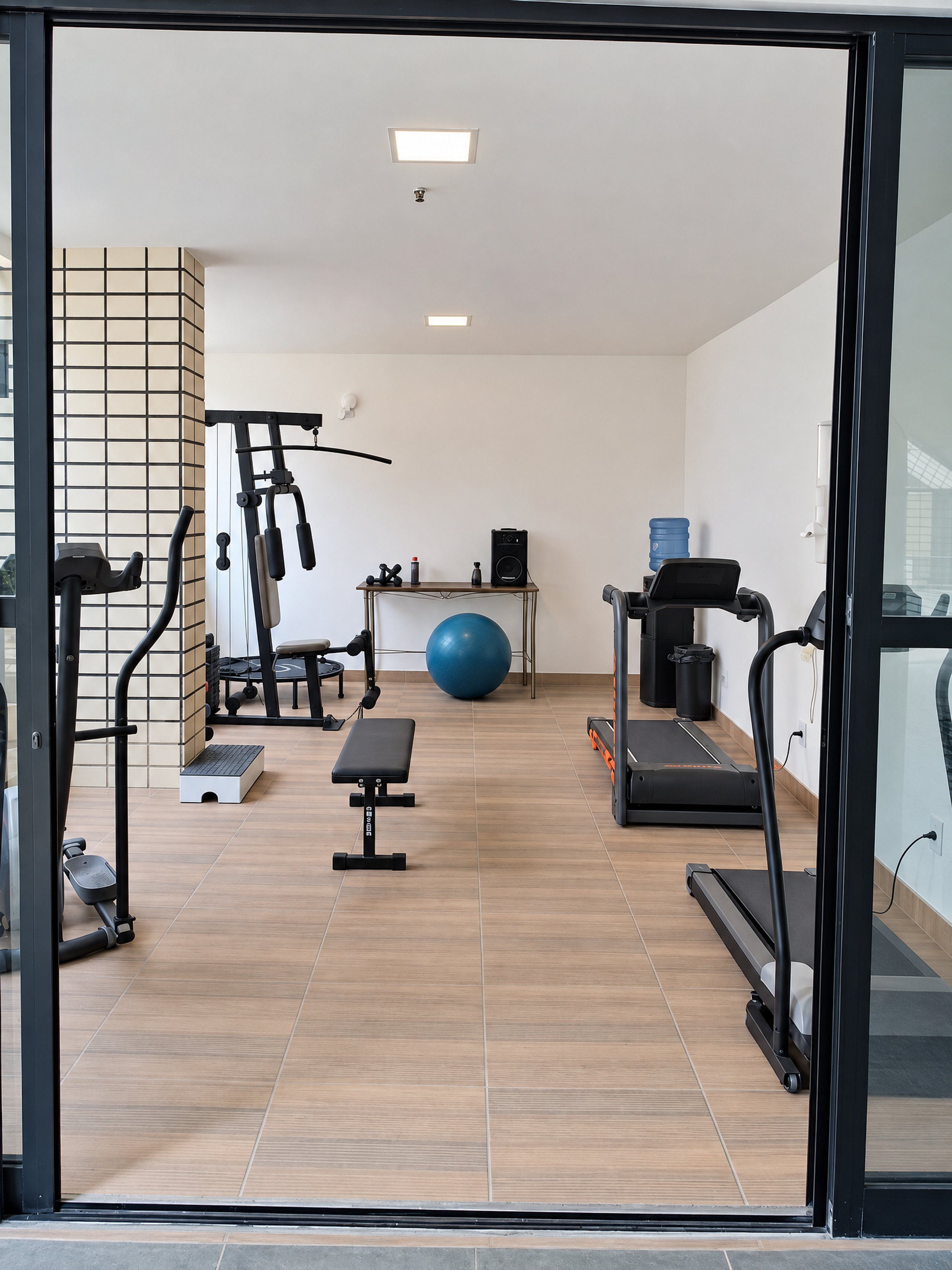 A gym with exercise equipment, a blue exercise ball, and a treadmill.