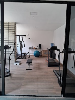 A home gym with exercise equipment, a blue exercise ball, and a treadmill. - Ape Familia 200 Metros da Feirinha Beira mar 502 (Fortaleza)