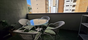 A balcony with wicker chairs, a glass table, and a view of buildings. - Ape Familia 200 Metros da Feirinha Beira mar 502 (Fortaleza)