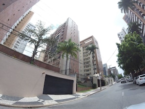 A street view with tall buildings, a gated entrance, and parked cars. - Ape Familia 200 Metros da Feirinha Beira mar 502 (Fortaleza)