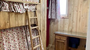 Una cama litera con escalera, un escritorio y una ventana en una habitación de madera.