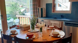 Un comedor con mesa de madera, sillas y vista al exterior.