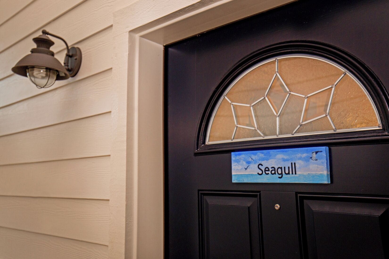 A black door with a blue sign reading "Seagull" and a decorative glass window above it.