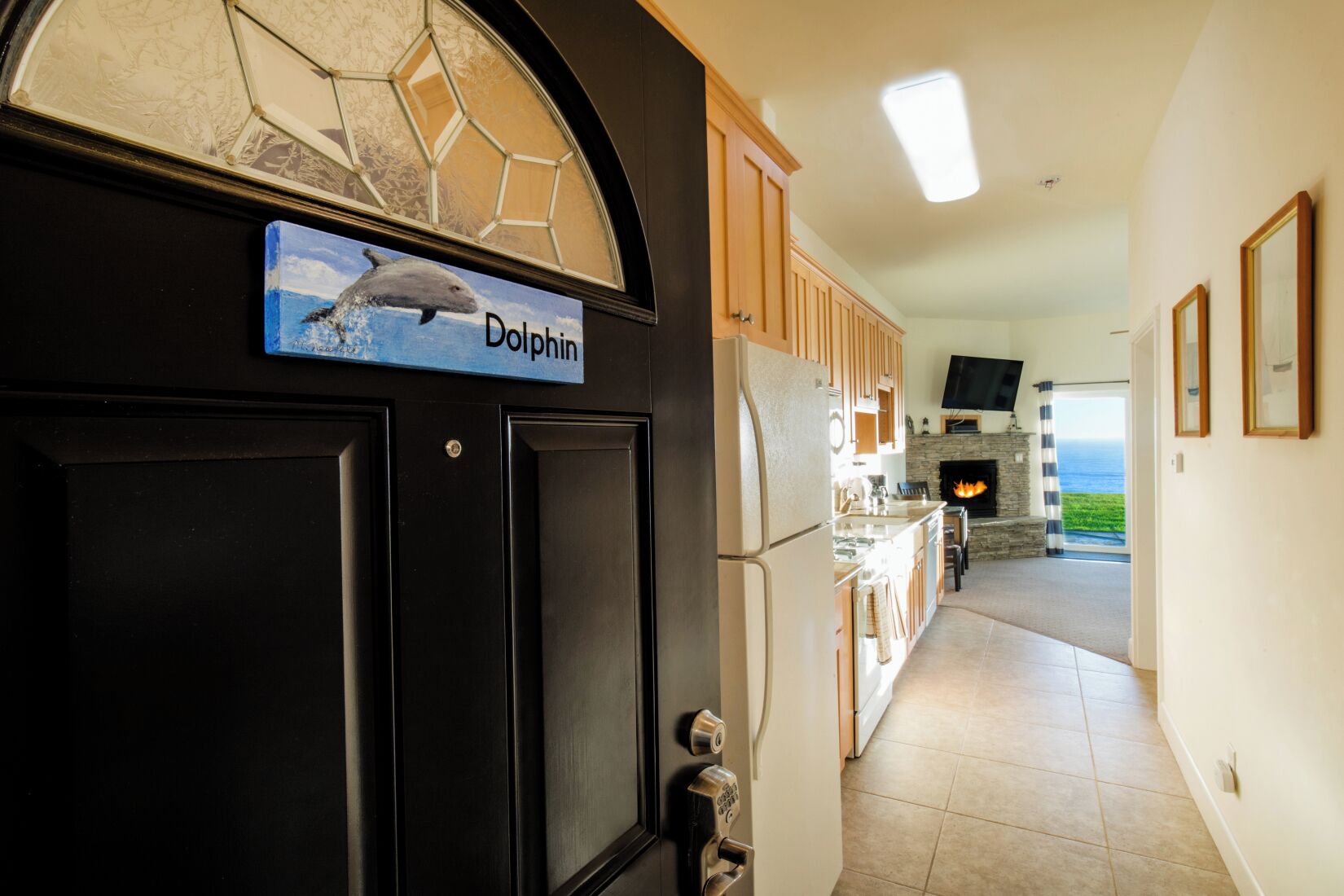 A kitchen with a stone fireplace, a sign reading "Dolphin", and a view of the ocean through a window.