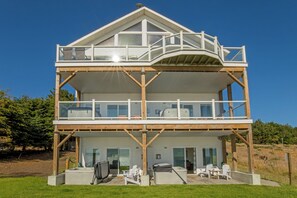 A two-story building with a balcony on the upper level, large windows, and a deck area with outdoor furniture. - Spyglass inn (Shelter Cove)