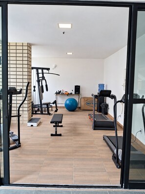 A gym with exercise equipment, a blue exercise ball, and a water dispenser. - Ape Familia 3 Quartos 200m da Feirinha Beira mar (Fortaleza)