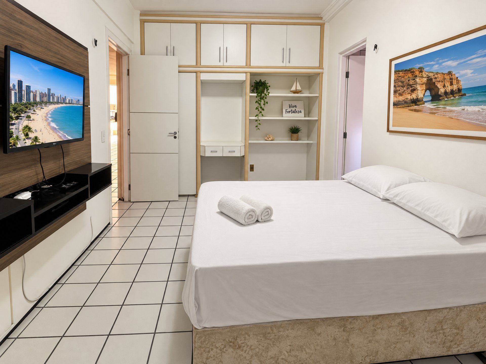 Une chambre d’hôtel avec un lit, une télévision, une armoire et un tableau représentant une plage.