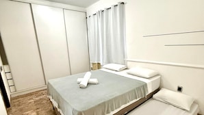 Une chambre d’hôtel comprenant un lit, un lit plus petit, une salle de bain et un espace douche.
