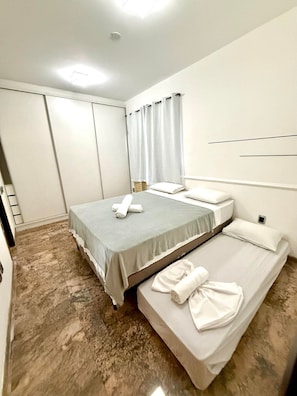 A hotel room with a bed, a smaller bed, a bathroom, and a shower area. - Apto Preferido Pelas Familias, 200m da Beira mar (Fortaleza)