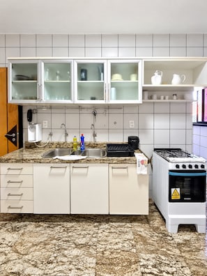A kitchen with white cabinets, a granite countertop, a sink, a stove, and a tiled backsplash. - Apto Preferido Pelas Familias, 200m da Beira mar (Fortaleza)