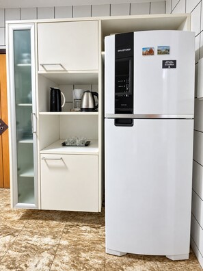 A white refrigerator with a freezer compartment, a coffee maker, and a kettle on the shelf. - Apto Preferido Pelas Familias, 200m da Beira mar (Fortaleza)