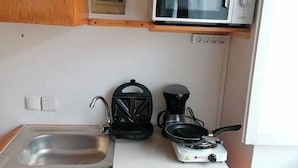 A compact kitchen with a sink, a microwave, a kettle, and a coffee maker.