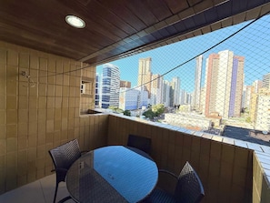 Ein Zimmer mit großem Fenster und Blick auf die Stadt, einem runden Tisch und zwei Stühlen.