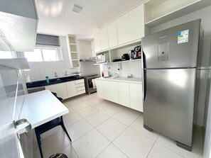 Eine moderne Küche mit weißen Schränken, einem Edelstahl-Kühlschrank und einer Mikrowelle.