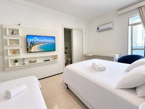 A hotel room with a bed, a TV on the wall, a desk, and a window. - Apartamento Familia Todo Reformado 4 Quartos (Fortaleza)