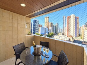 A balcony with a city view, a round table, two chairs, a champagne bucket, and two glasses. - Apartamento Familia Todo Reformado 4 Quartos (Fortaleza)
