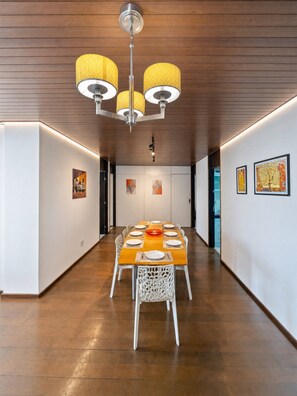 Un espace de restauration moderne avec une longue table, des chaises blanches et un lustre.