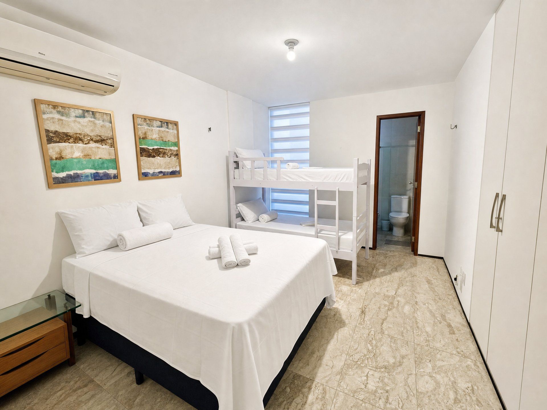 A bedroom with a bunk bed, a single bed, a glass table, and a wardrobe.