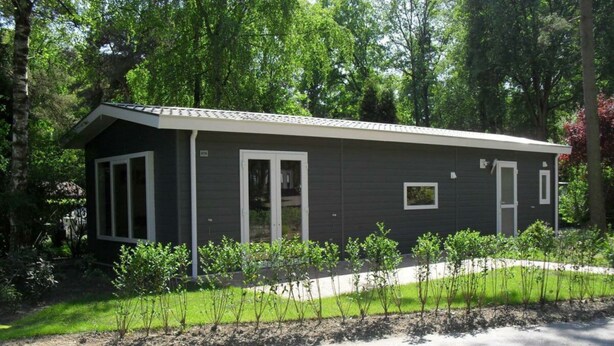 En envåningsbyggnad med en mörk fasad, vitmålade fönsterramar och en liten veranda.