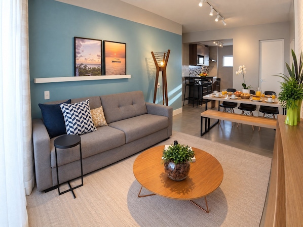 A modern living room with a sofa, coffee table, and a dining area with a breakfast setup. - Beautiful Apartment With sea View 2 Bedrooms (Fortaleza)