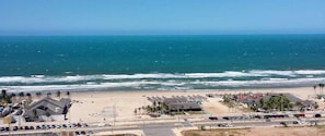 A beachside view with a parking lot, beach umbrellas, and a clear view of the ocean. - Beautiful Apartment With sea View 2 Bedrooms (Fortaleza)