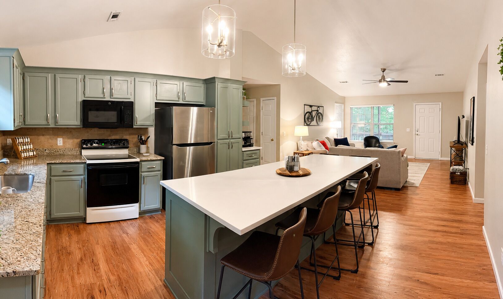 A modern kitchen with a central island, stainless steel appliances, and a dining area with bar stools.