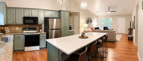 A modern kitchen with a central island, stainless steel appliances, and a dining area with bar stools.