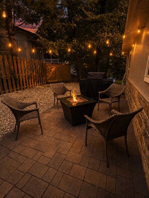 An outdoor patio area with a fire pit, wicker furniture, and string lights. - Ozark Calling -- Ride-In Ride-Out MTB Basecamp, Premium Location (Bella Vista)