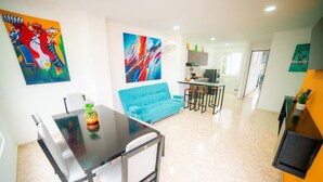 A modern living space with a dining area, a blue sofa, and a kitchen in the background. - Departamento moderno Edimar 202 (Magdalena)