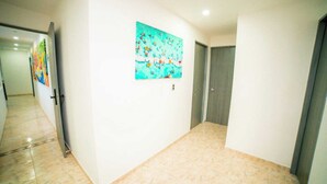 A hallway with a tiled floor, a door, and a colorful painting on the wall. - Departamento moderno Edimar 202 (Magdalena)