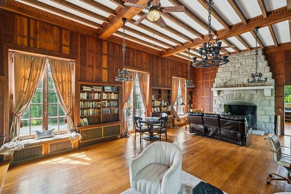 A spacious room with wooden walls, a fireplace, and bookshelves.