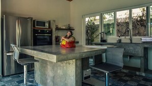 Cocina con una isla central, electrodomésticos de acero inoxidable y un amplio ventanal.