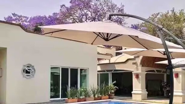 Zona de piscina con piscina, sillas de descanso y una sombrilla.