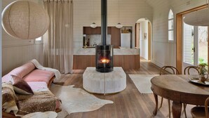 Un interior acogedor con chimenea central, muebles de madera y vistas al exterior.