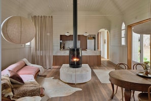 Een knus interieur met een centraal gelegen open haard, houten meubels en uitzicht naar buiten.