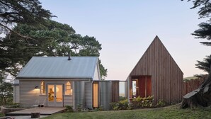 Una casa moderna con techo de metal, estructura de madera con techo triangular y un patio cubierto de césped.