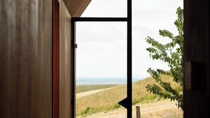 Una habitación con un amplio ventanal, una cama y vistas a un paisaje cubierto de hierba.
