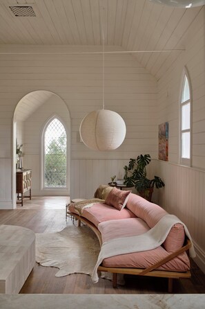 Een kamer met een gebogen bank, een hanglamp en een groot raam met uitzicht.