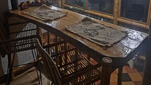 A dining table with a rustic design, surrounded by wooden chairs.