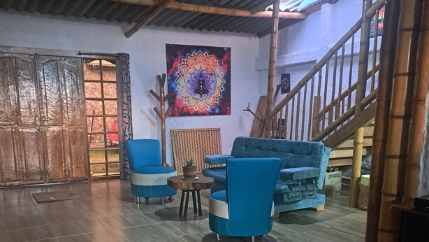 A spacious room with a high ceiling, a wooden staircase, and a large window.