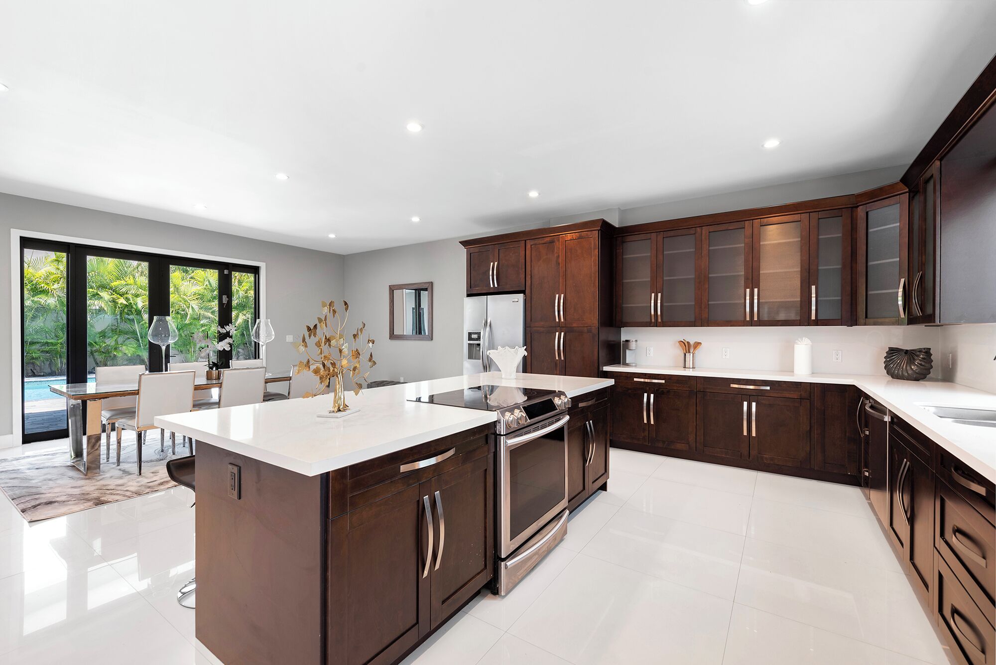 A modern kitchen with dark wooden cabinets, stainless steel appliances, and a large island.