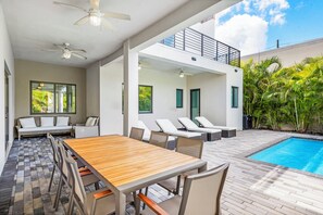 A modern outdoor patio with a pool, lounge chairs, and a dining area. - 10BR Modern Spacious New Villa, Pool, Games & Grill (Miami)