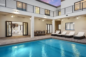 A modern indoor pool area with lounge chairs, a dining area, and a ceiling with a skylight. - 10BR Modern Spacious New Villa, Pool, Games & Grill (Miami)