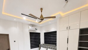 Ein modernes Schlafzimmer mit Bett, Deckenventilator, Kleiderschrank und Schreibtisch.