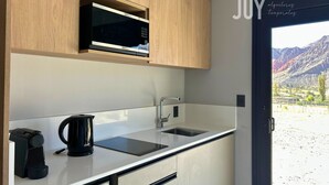 A modern kitchen with wooden cabinets, a microwave, a kettle, and a sink. - Casiraaaaa (Purmamarca)